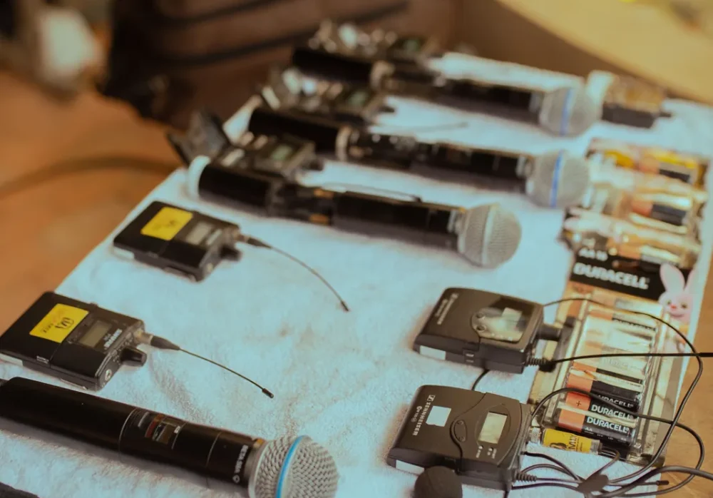 Wireless handheld and belt-pack microphones laid out on a table ready for an event sound check